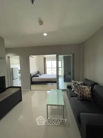 Modern apartment interior with sleek living room and bedroom view, featuring contemporary furniture and neutral tones.