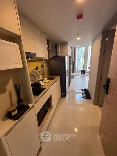 Modern kitchen with sleek cabinetry and open layout leading to a bright living area with city views.