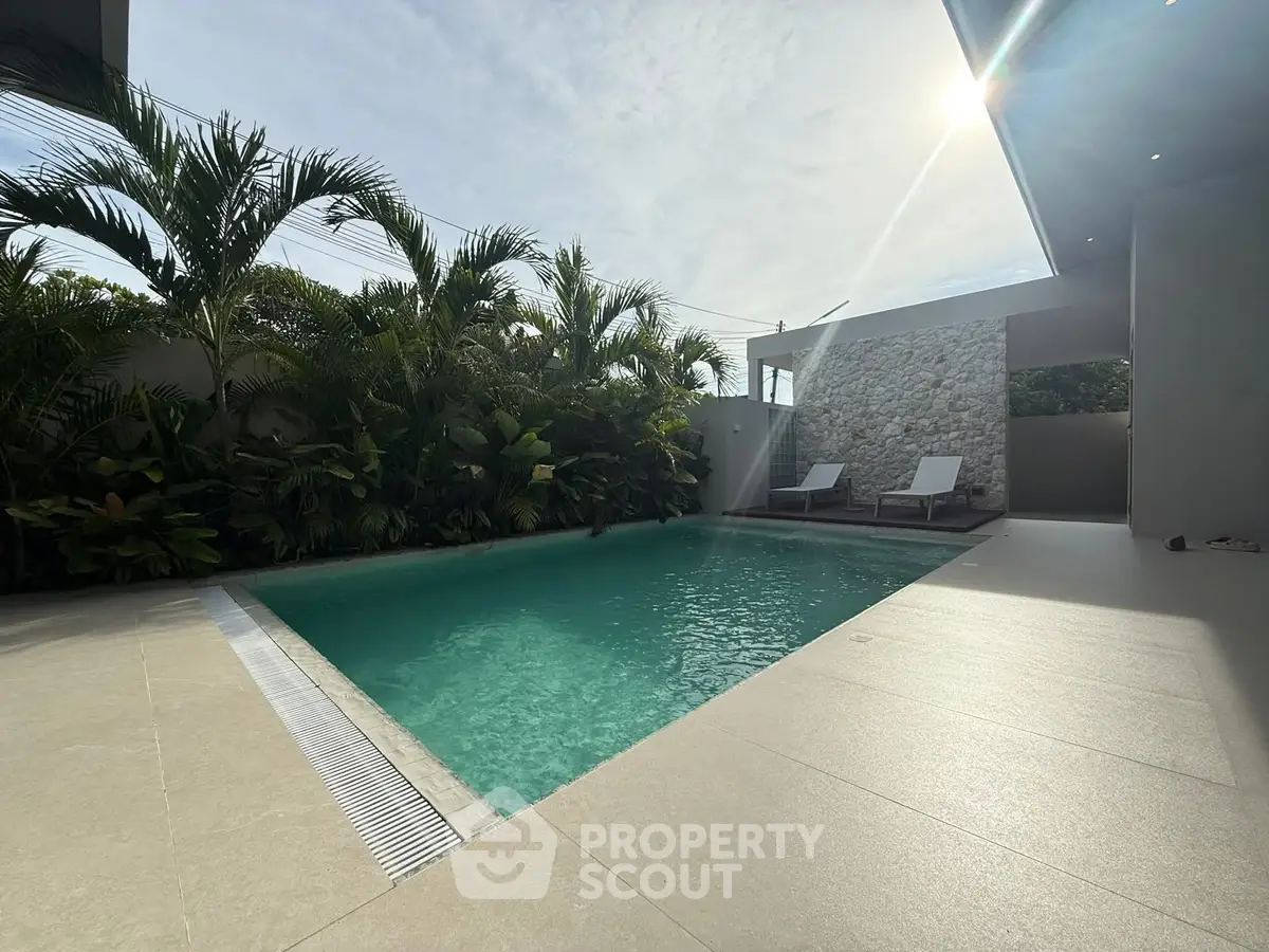 Luxurious private pool with sun loungers and lush greenery, perfect for relaxation and leisure.