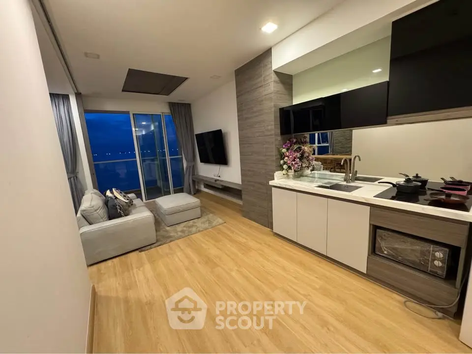 Modern open-layout living room with sleek kitchen and stunning evening view.