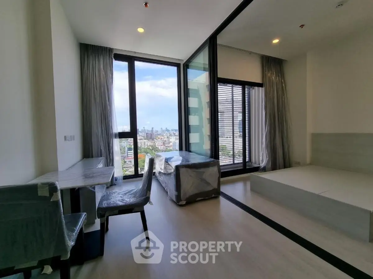 Modern apartment with city view, featuring large windows and sleek interior design.