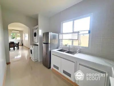 Modern kitchen with sleek appliances and open layout leading to dining area