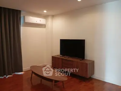 Modern living room with sleek wooden furniture and mounted air conditioner.