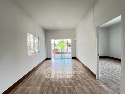Spacious empty living room with tiled flooring and large windows for natural light.
