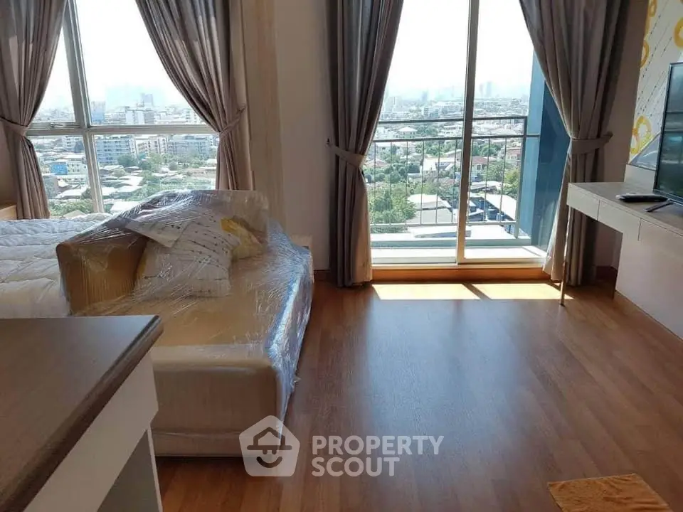 Spacious living room with large windows offering stunning city views, modern decor, and natural light.