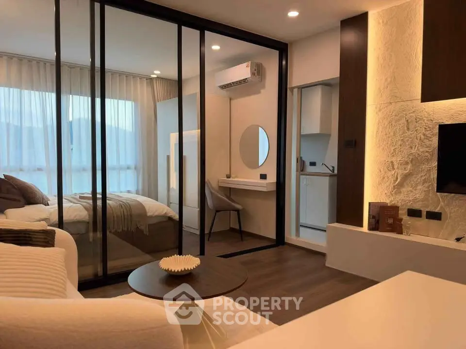 Modern studio apartment with glass partition, cozy living area, and stylish decor.
