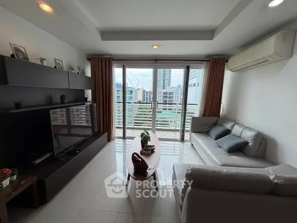 Modern living room with sleek furniture and city view from large windows.