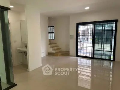 Spacious modern living room with large windows and staircase in a contemporary home.