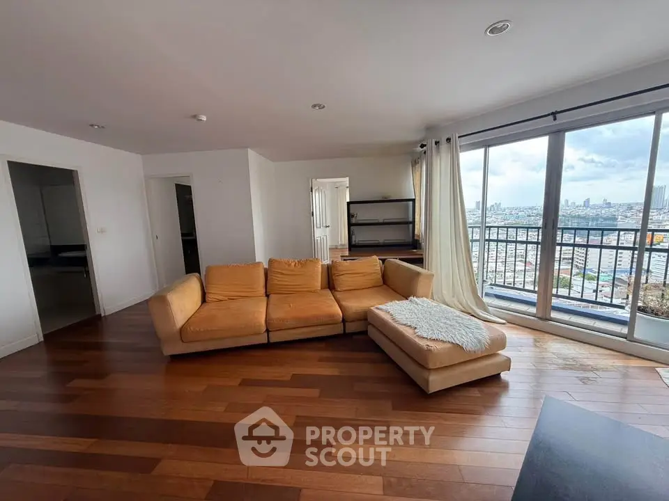 Spacious living room with panoramic city view and modern furnishings.