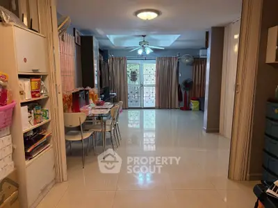 Spacious living room with dining area and large windows, featuring modern furniture and bright lighting.