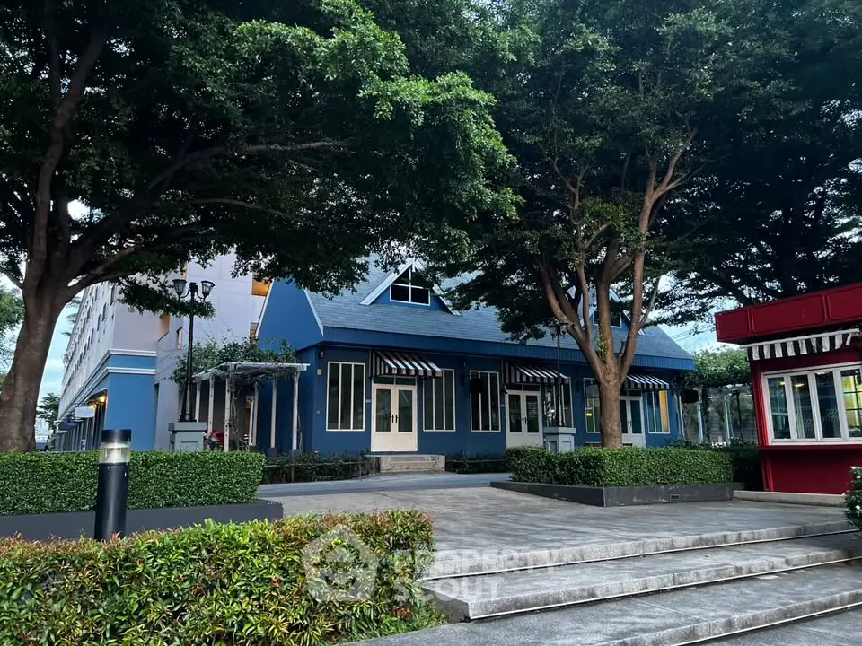Charming blue building with lush greenery and inviting entrance in serene setting.