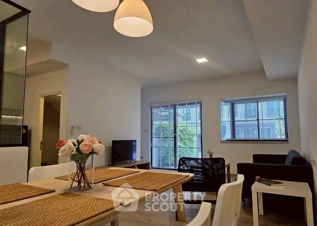 Modern living room with stylish decor and natural light, featuring a cozy seating area and dining space.