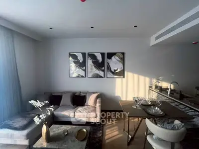 Modern living room with elegant decor and open kitchen layout, featuring stylish furniture and natural light.