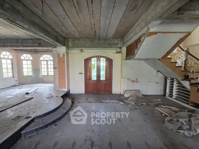 Spacious interior with rustic charm, featuring large windows and unique architectural details, ideal for renovation.