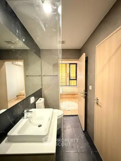 Modern bathroom with sleek design and view into a cozy bedroom