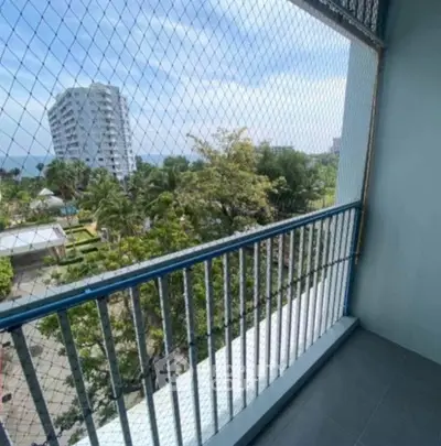 Spacious balcony with safety netting and scenic view of lush greenery and distant buildings.