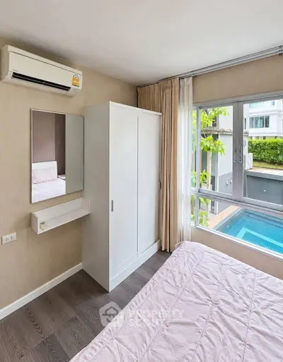 Modern bedroom with pool view, featuring air conditioning and sleek wardrobe design.