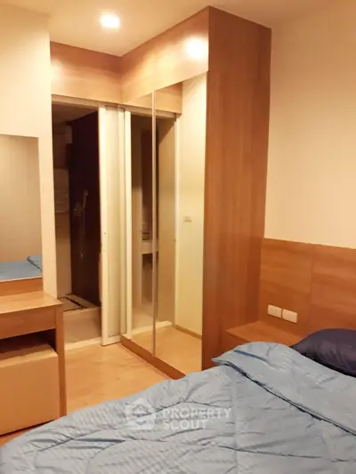 Cozy bedroom with wooden accents and mirrored closet doors, perfect for modern living.