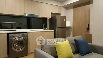 Modern apartment interior with stylish kitchen and cozy living area featuring a washing machine and colorful cushions.