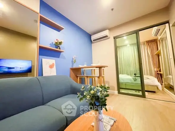 Modern living room with blue accent wall and cozy bedroom view.