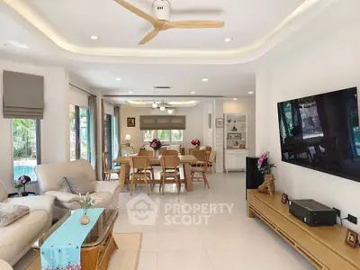 Spacious living room with elegant decor and open dining area, featuring modern furniture and large windows.