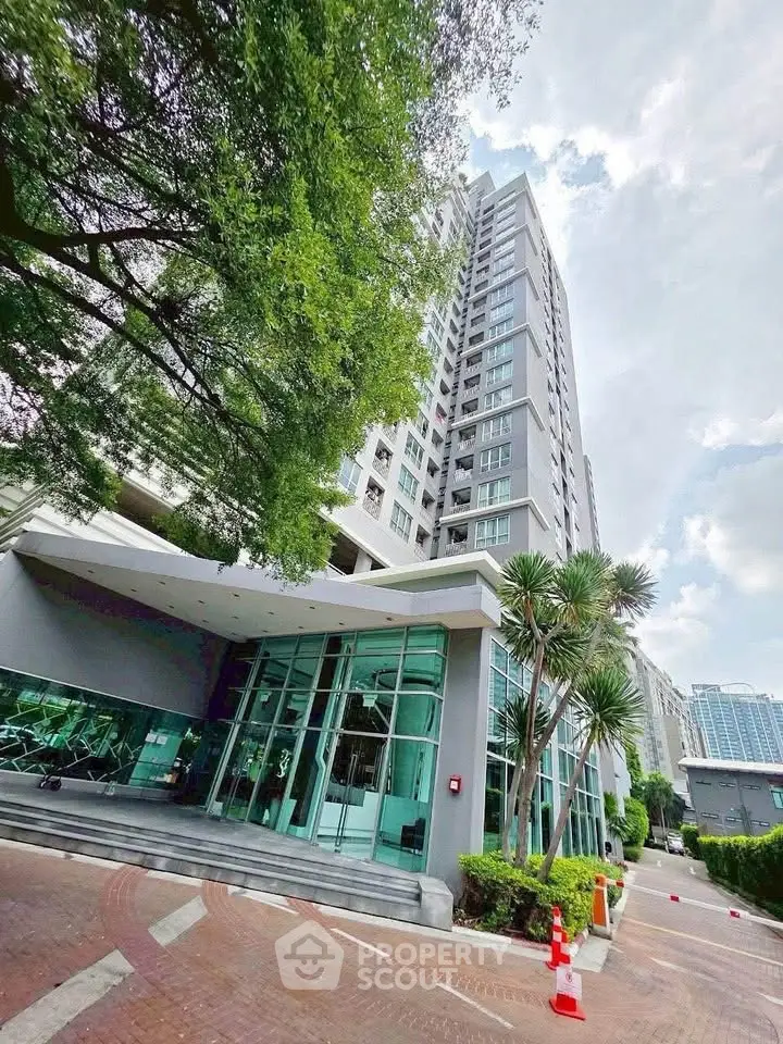 Modern high-rise building with lush greenery and sleek entrance