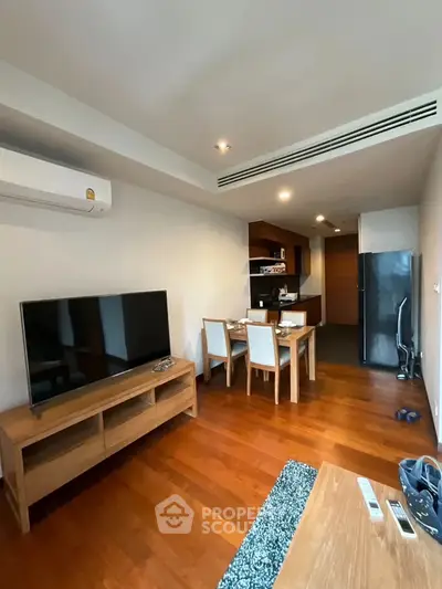 Modern living room with wooden flooring, dining area, and open kitchen layout in a stylish apartment.