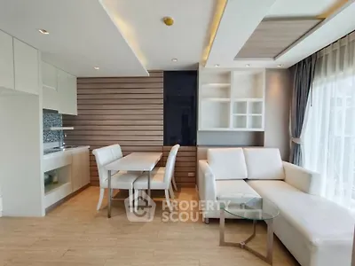 Modern open-layout living room with stylish kitchen and dining area, featuring elegant furniture and natural light.