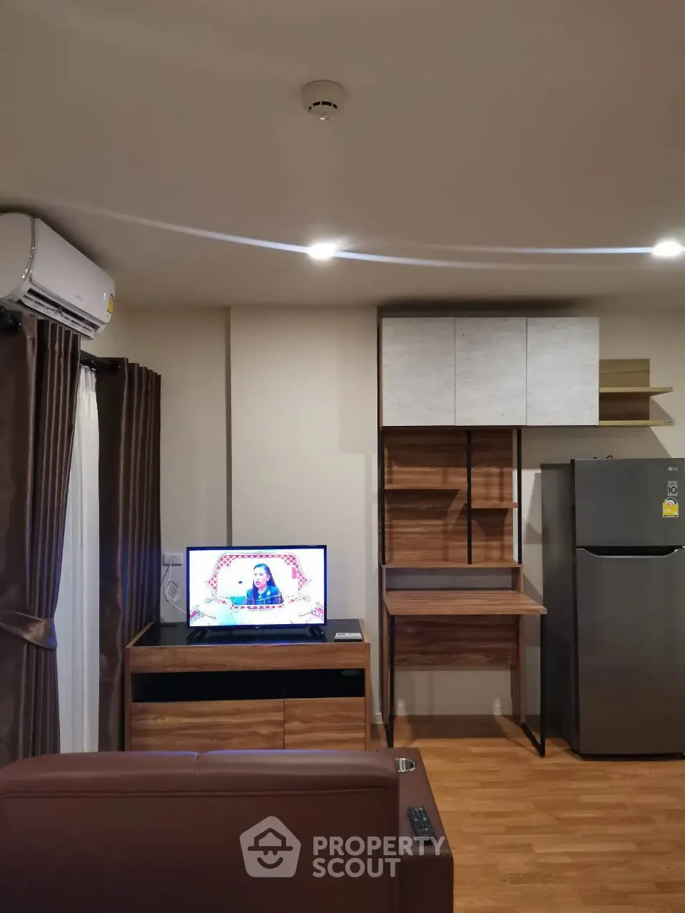 Modern living room with TV, air conditioning, and stylish wooden cabinets.