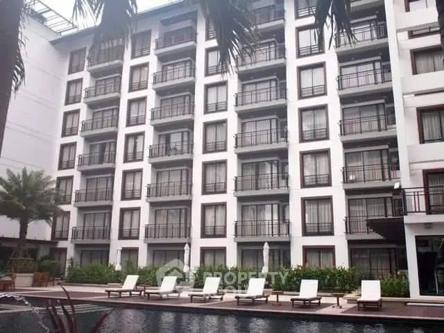 Modern apartment building with poolside view and lounge chairs, perfect for luxury living.
