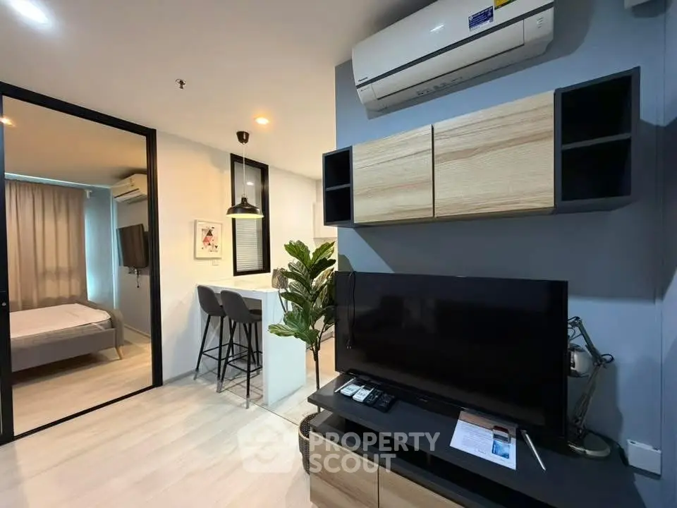 Modern living room with sleek TV setup and open view to cozy bedroom