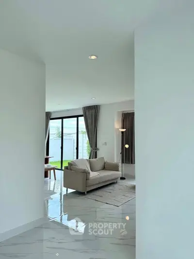 Spacious modern living room with sleek marble flooring and large windows opening to a garden view.