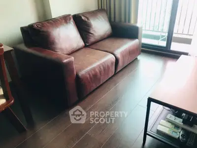 Cozy living room with brown leather sofa and wooden flooring, perfect for relaxation.
