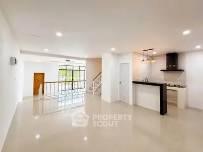 Spacious open-plan living room with modern kitchen and elegant staircase