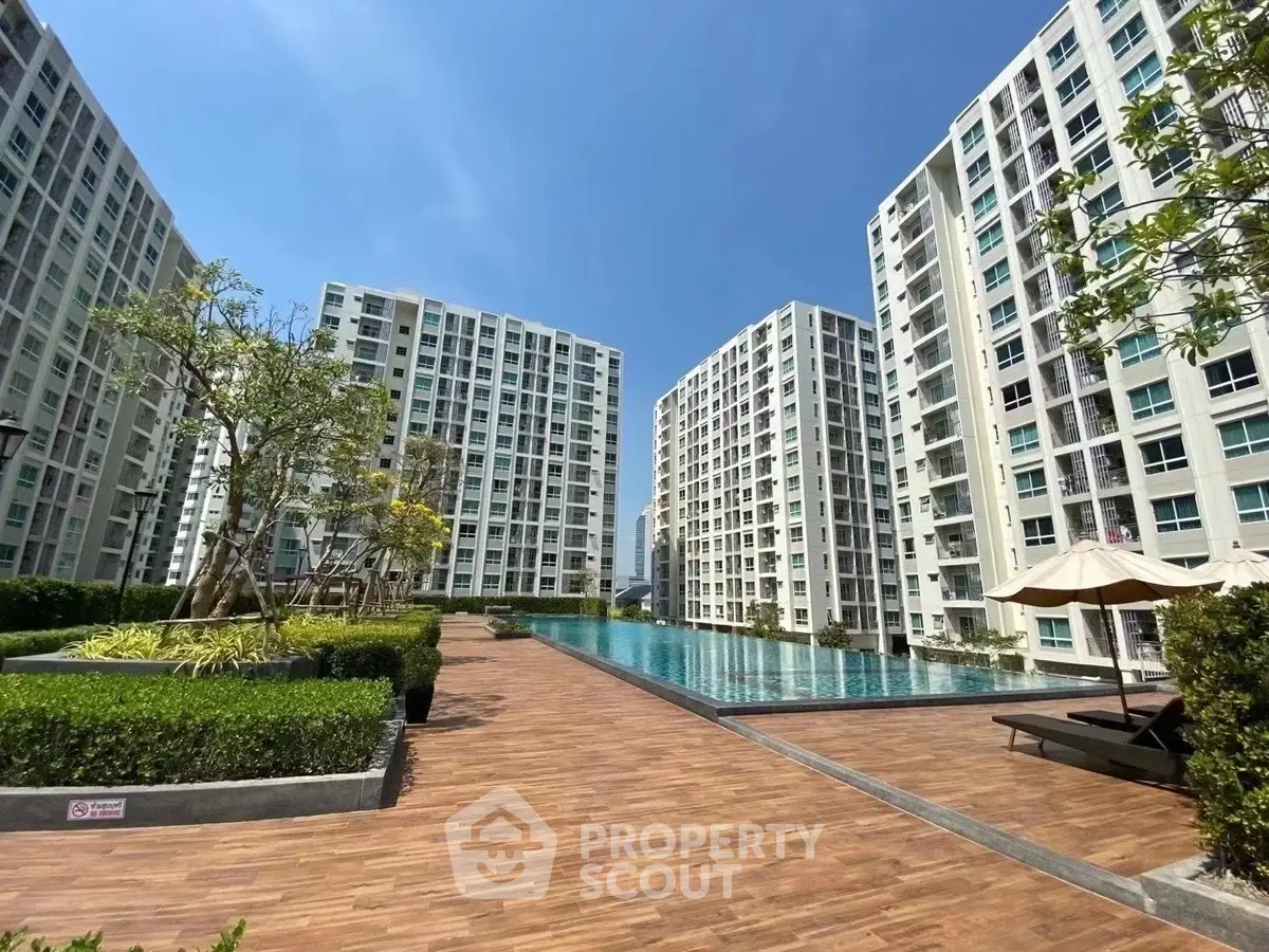 Luxurious condominium complex with a stunning outdoor pool and modern architecture under a clear blue sky.
