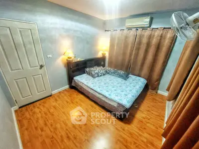 Cozy bedroom with wooden flooring and soft lighting, featuring a comfortable bed and elegant curtains.