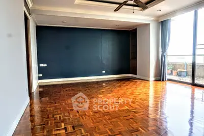 Spacious living room with parquet flooring and large windows for natural light.