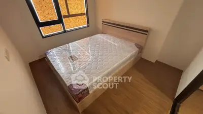Modern bedroom with wooden flooring and a new mattress on a stylish bed frame.