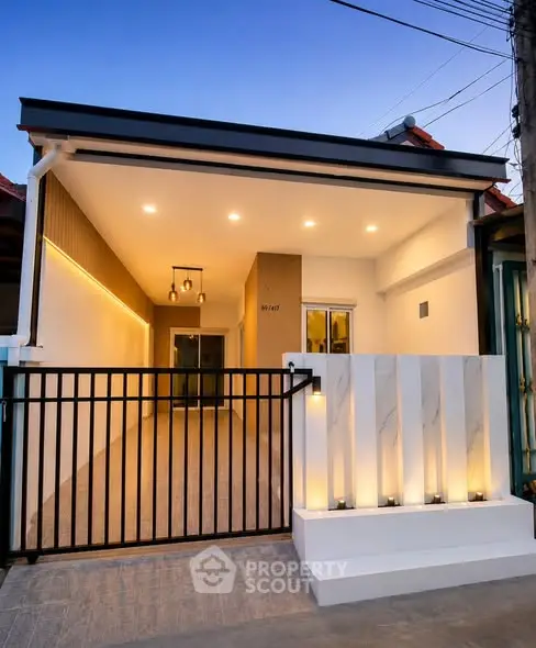 Modern single-story house with sleek exterior lighting and gated entrance at dusk.