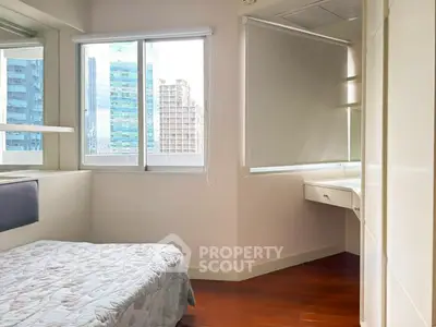 Cozy bedroom with city view, featuring a comfortable bed and ample natural light from large windows.