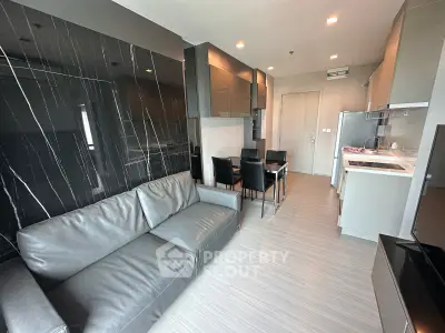 Modern living room with sleek kitchen, stylish black marble wall, and comfortable gray sofa in open layout apartment.
