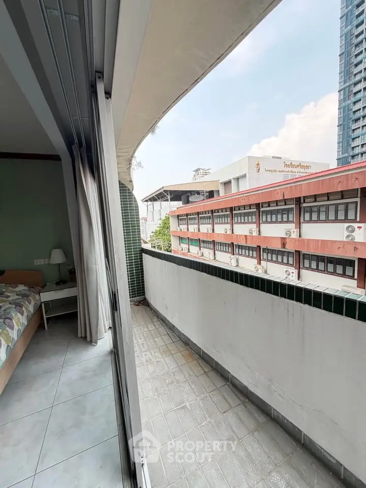 Spacious balcony with city view adjacent to cozy bedroom in urban apartment