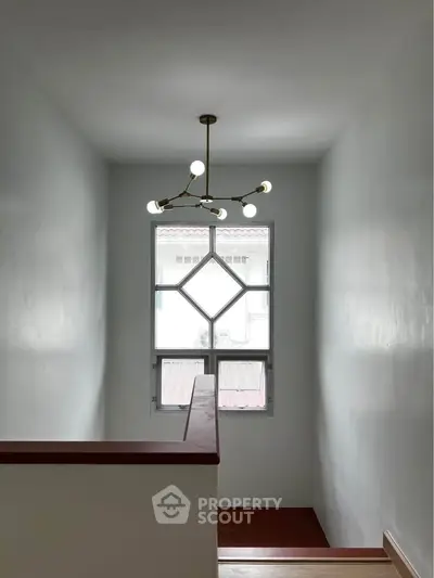 Minimalist staircase with modern chandelier and window view