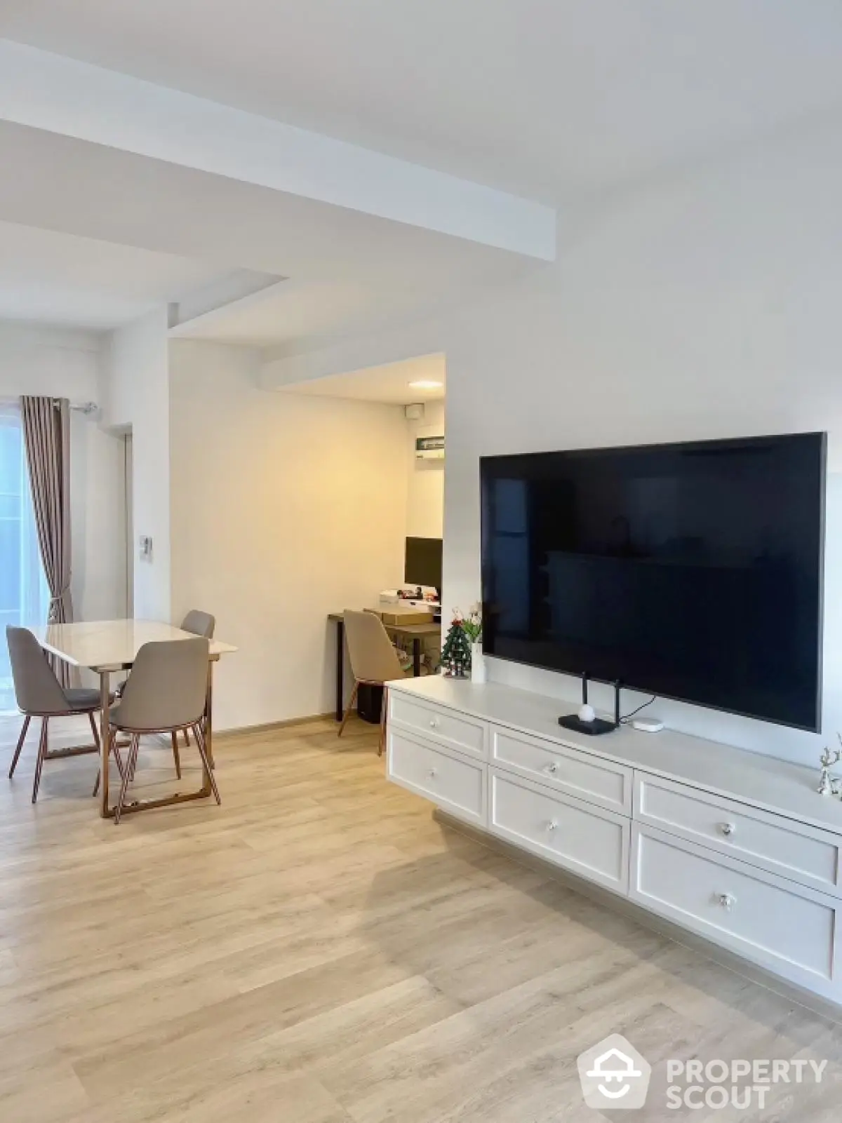 Modern living room with large TV and dining area, featuring stylish furniture and wooden flooring.