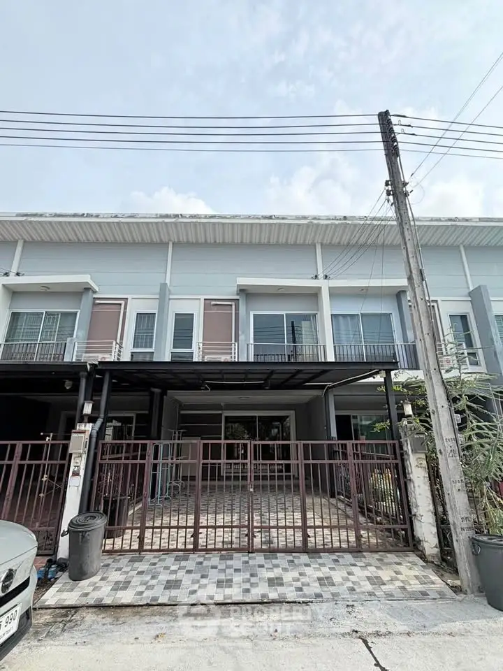 Modern townhouse exterior with gated entrance and tiled driveway