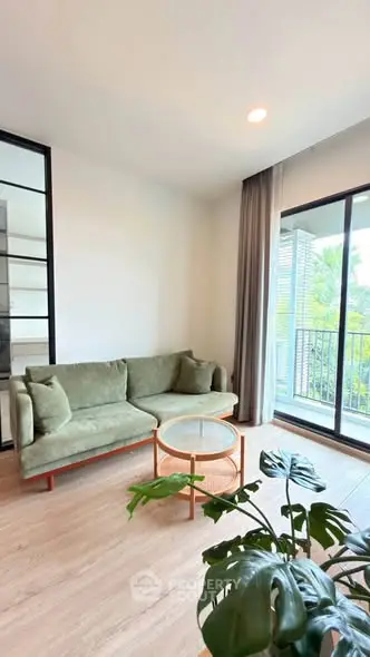 Modern living room with green sofa, glass coffee table, and balcony view.