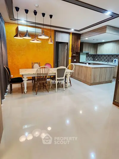 Spacious dining area with modern kitchen and stylish lighting in open layout apartment.