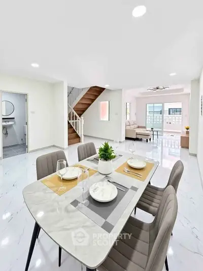 Spacious modern dining area with elegant table setting and open view to living room.