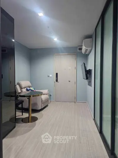 Modern living room with sleek design, featuring a cozy armchair, wall-mounted TV, and stylish glass partitions.