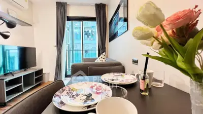 Modern living room with dining area and balcony view, featuring stylish decor and natural light.